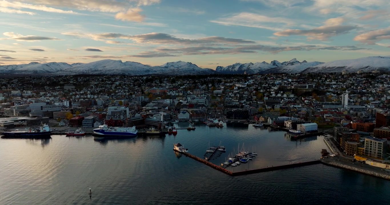 Stadt Tromsø, Hafen, Yachthafen und schneebedeckte Berge im Hintergrund im Frühwinter in Norwegen. Luftaufnahme vorwärts, mit Platz für Text