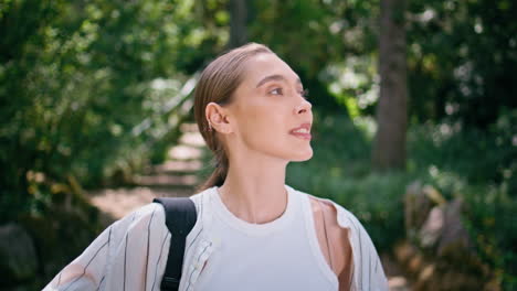 active woman strolling park looking around on beautiful fresh greenery close up.