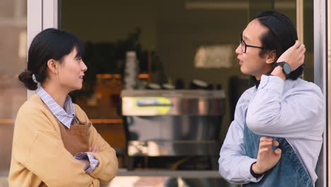 waiter and waitress having conversation during a break at work in cafe