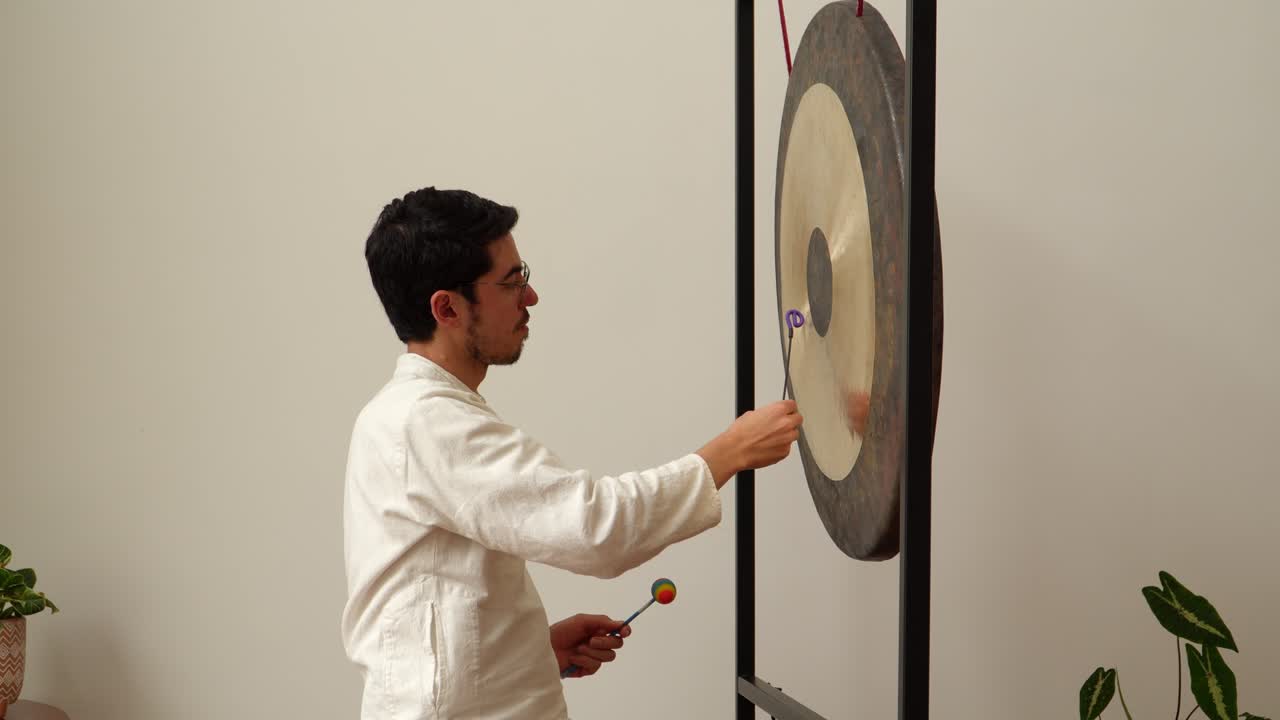 Man playing a gong with mallets using his hands