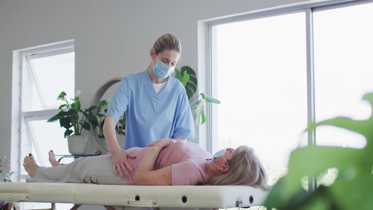Operatrice sanitaria che massaggia i fianchi di una donna anziana a casa