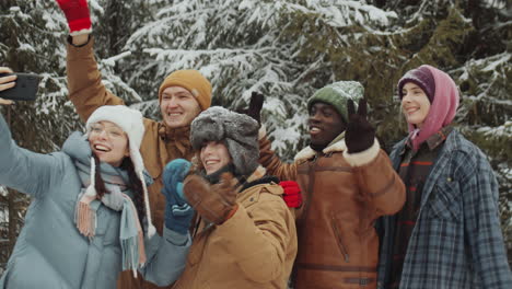 happy friends taking selfie in winter forest