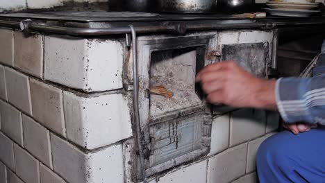 el hombre abre la puerta y pone madera en una cocina rústica antigua