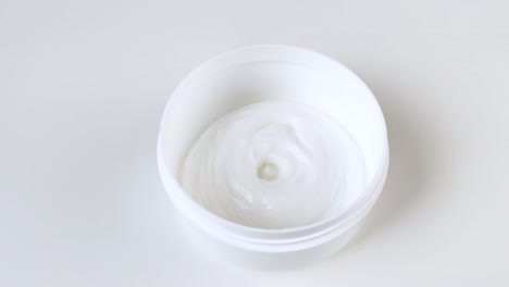 la crema viene versata in un barattolo rotondo di plastica