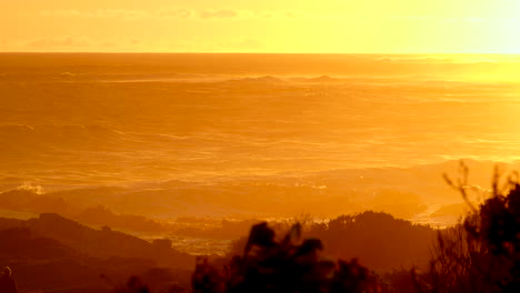 yellow and orange sunset sky over waves rolling in toward rocky coastline