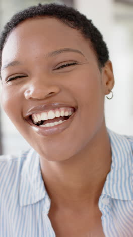 vertical video of happy african american having video call and waving, slow motion