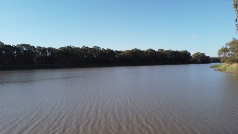 Drone-Volando-Desde-La-Orilla-Del-Río-Sobre-Un-Río