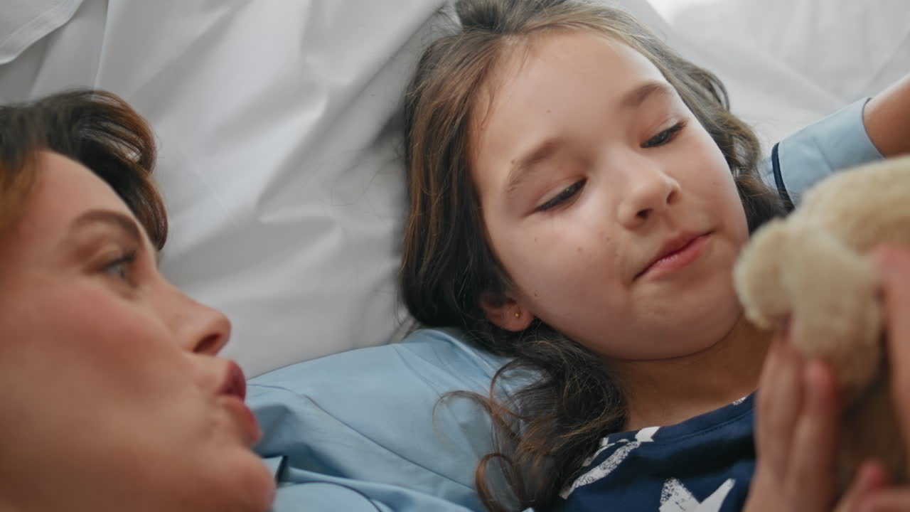 Cute family lying bedding closeup. woman talking kid in bed at weekend