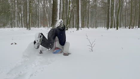 playful girl rolls forward on the heavy snow in the forest during winter in germany - slow motion