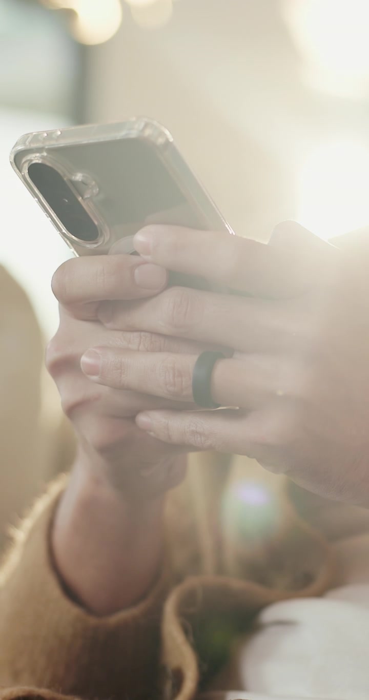 Primo Piano di una Persona che Usa lo Smartphone con un Anello Intelligente