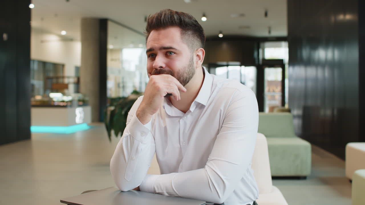 Sad businessman using laptop loses becoming shocked sudden lottery results in modern hotel lobby