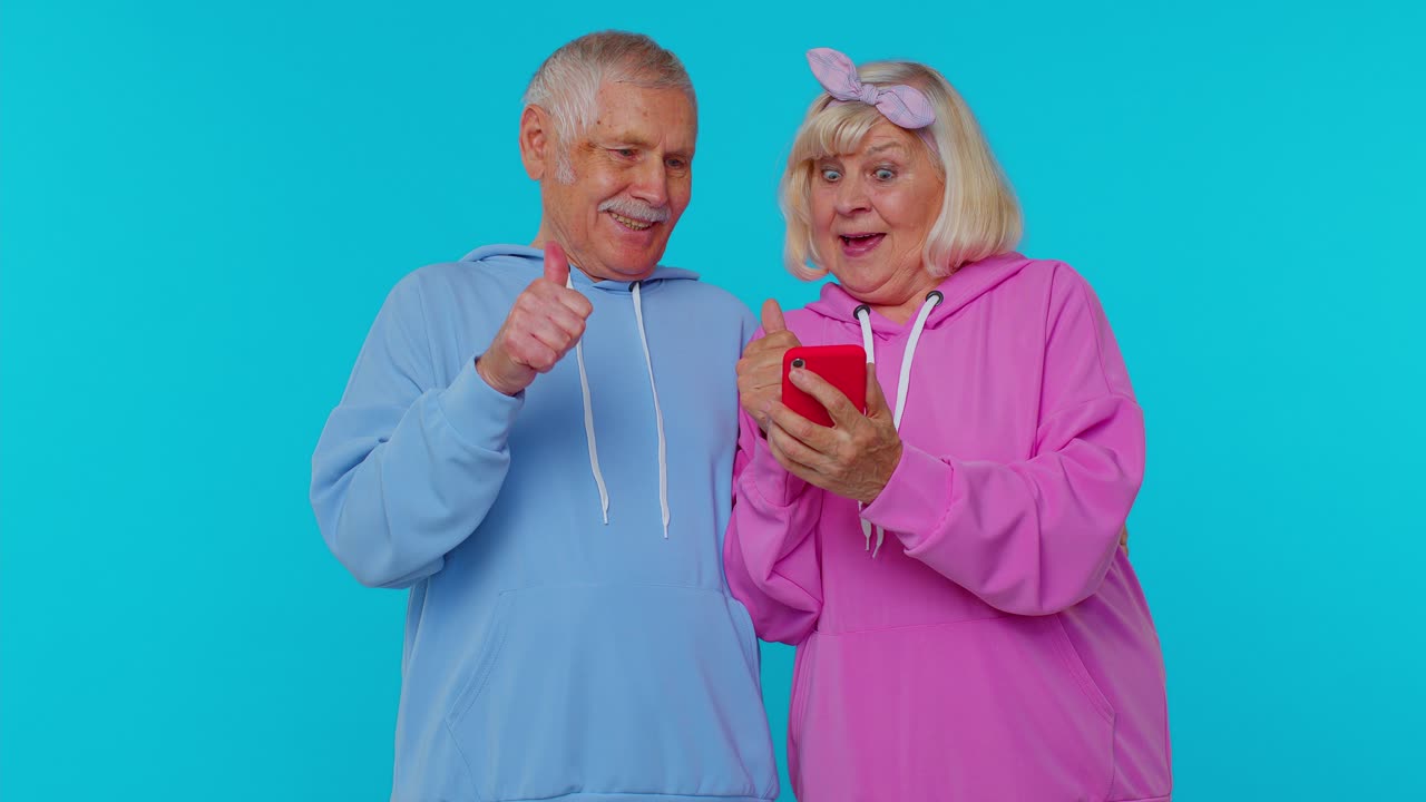 Happy senior couple man woman grandparents use mobile phone celebrating found out great big win news
