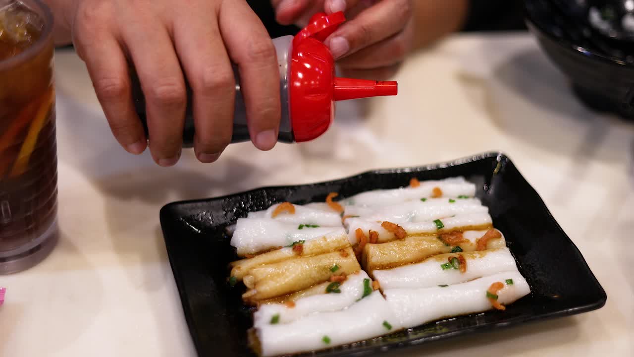 Pouring sauce over rice noodle rolls