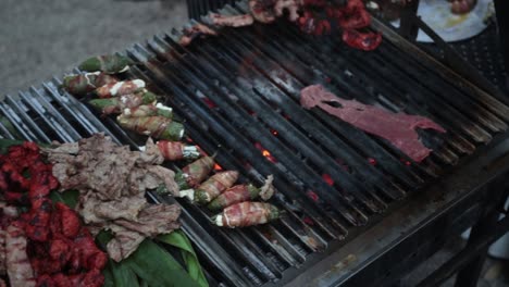 slow motion panning shot showing a chef cooking a selection of food on a open grill