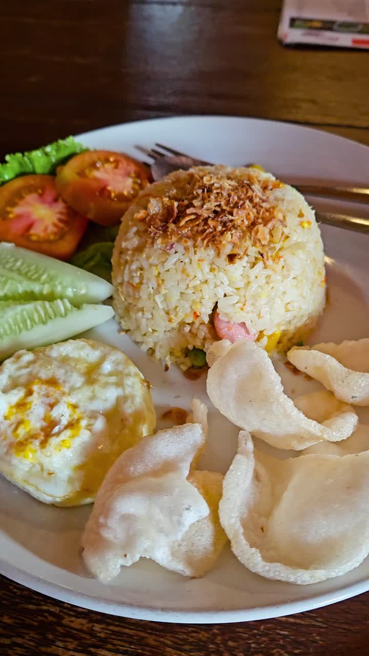 Nasi Goreng or fried rice with prawn chips on plate in Indonesia. Vertical