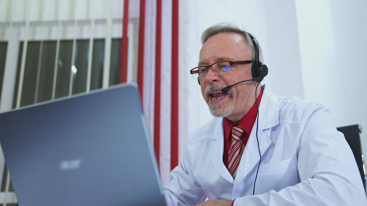 Médico en su consultorio con auriculares frente a su portátil. Concepto de telemedicina.
