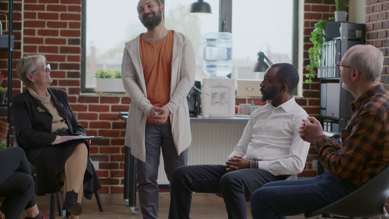 Cheerful man celebrating addiction progress with people applauding at aa group meeting