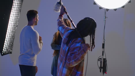 a film crew is shooting a scene in a studio with a camera and a microphone.