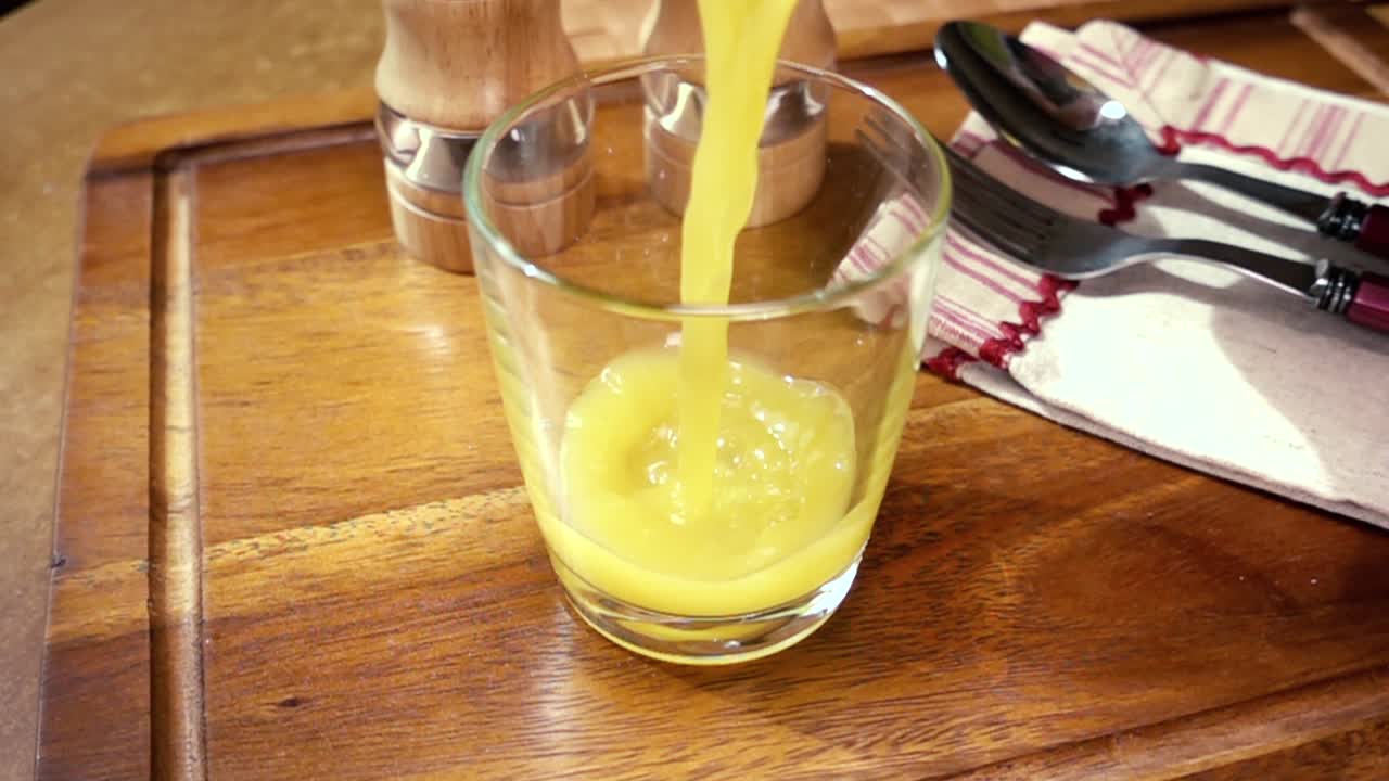 jugo de naranja en un vaso, el desayuno de la mañana, cámara lenta con seguimiento de rotación.