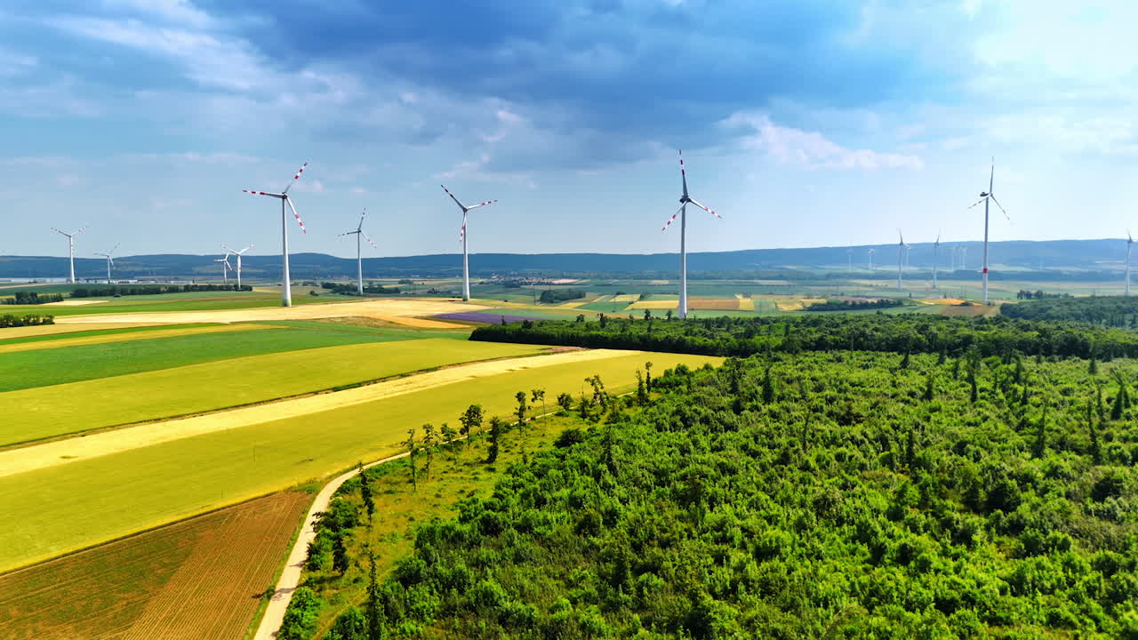 Stunning nature landscape divided into the fields. Numerous wind mills installed in the countryside. Grey clouds in the sky above