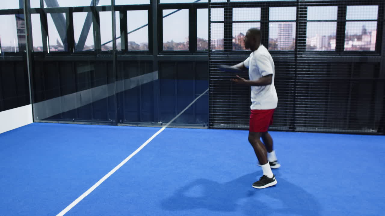 Man playing padel tennis on blue indoor court, preparing to serve ball