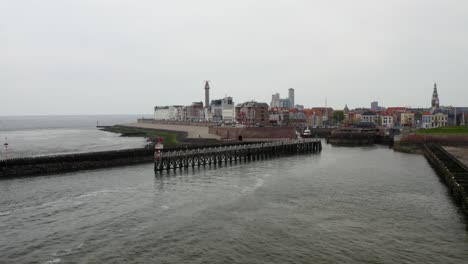 toma aérea sobre los rompeolas en la entrada del puerto con un panorama de una playa de ciudad vacía en vlissingen, países bajos