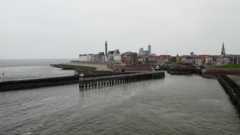 aerial shot over the breakwaters in the entrance to the harbor with a panorama of an empty city beach in vlissingen, the netherlands