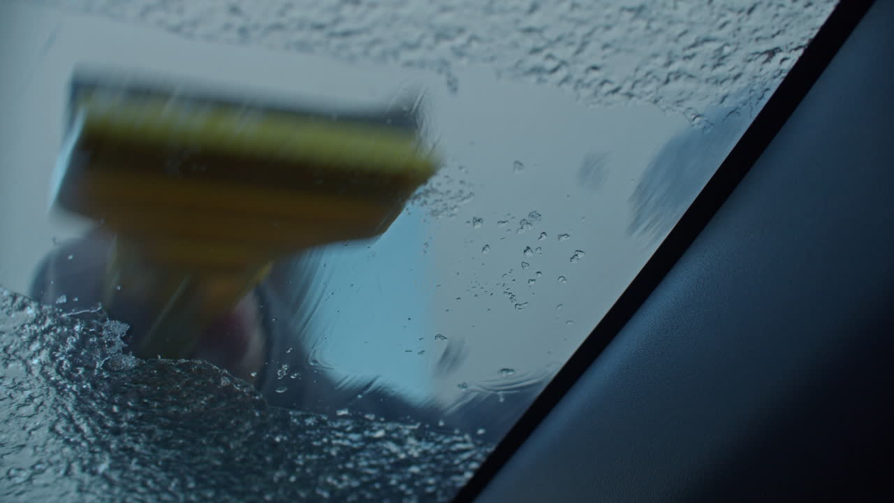 Looking out of the ride side of a car windshield while the glass getting cleaned from freezing rain