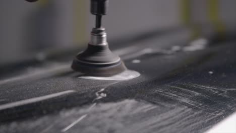 auto body technician using abrasive power tool on car bodywork close up slo mo