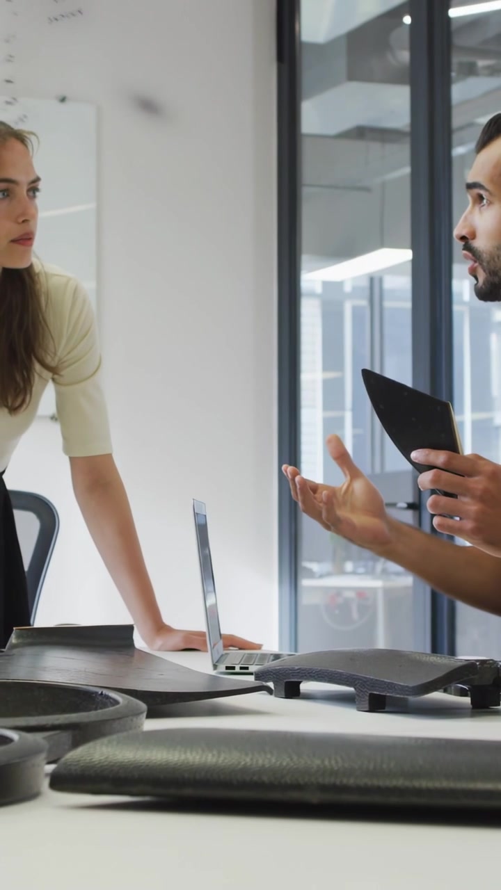 Vertical video: Man holding triangle part, starting design, woman leaning in, dotted glass sweeping