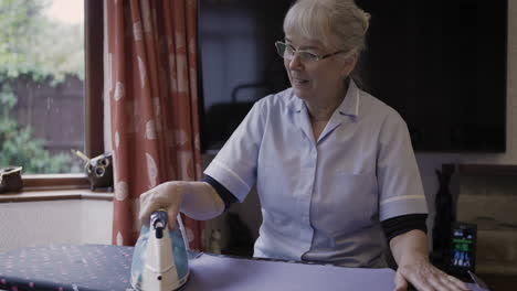 caregiver ironing clothes for elderly man