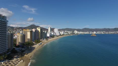 toma aerea con drone de la bahia de acapulco donde se ve la playa, el mar y los hoteles