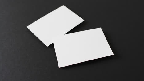 Close-up-of-blank-white-business-cards-on-black-background,-copy-space,-slow-motion