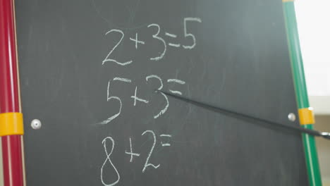 el maestro muestra tareas de matemáticas en la pizarra en el aula.