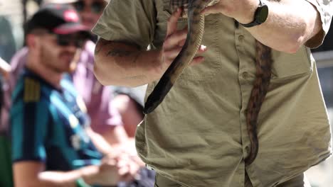 man showcasing snake to audience at zoo