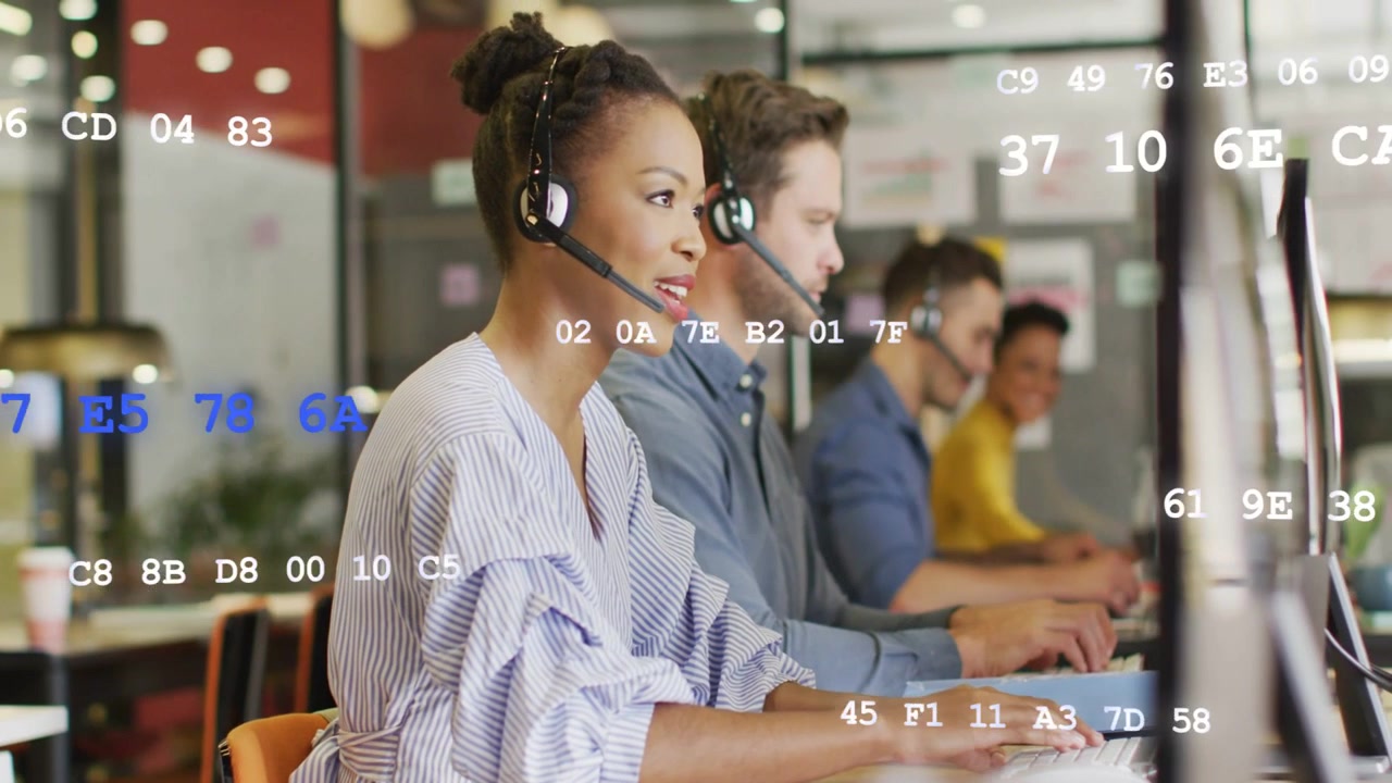 Call agent receiving call, talking on headset and typing, assisting caller, code overlay on screens