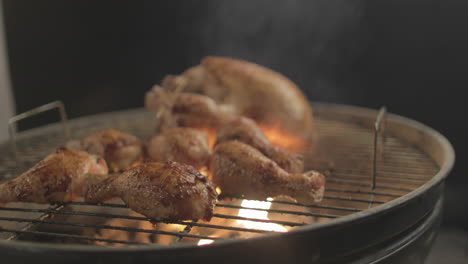 chicken drum sticks getting grilled on coal and fire with smoke coming up with black background shot raw and 4k eye level