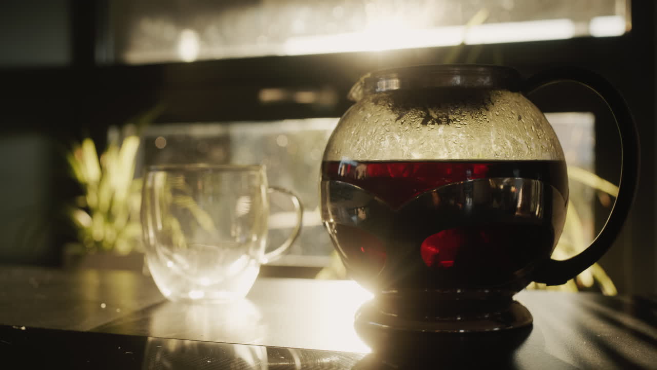 차  ⁇ 비에서 차를 유리 컵에 부어. 태양은 창문에서 빛나고, 아름답게 접시를 조명