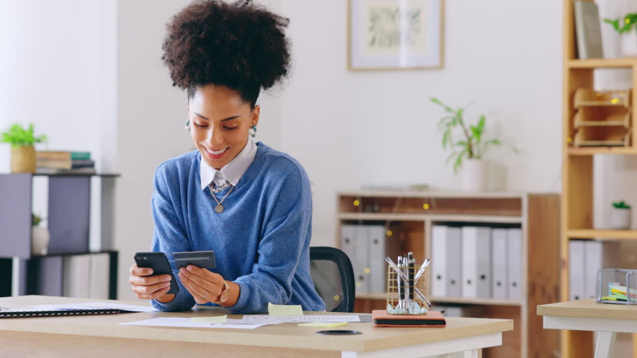 Donna in ufficio, carta di credito e telefono, felice