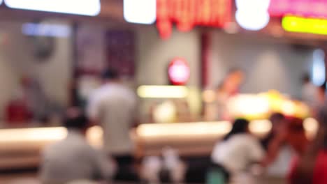 indistinct figures moving in a busy food court