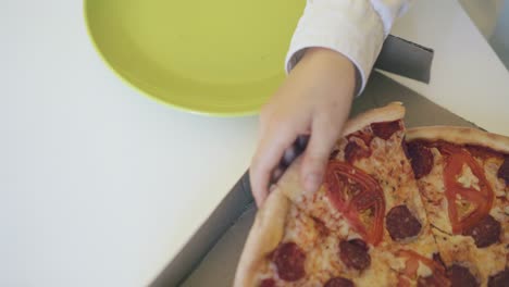 child puts large pizza slice on plate closeup upper view