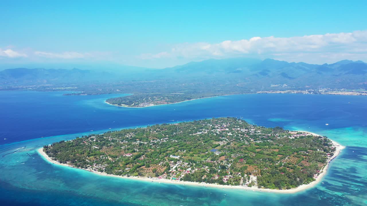 Big tropical island with resorts and villas for vacationers surrounded by white beach and blue turquoise lagoon on a misty morning in Indonesia