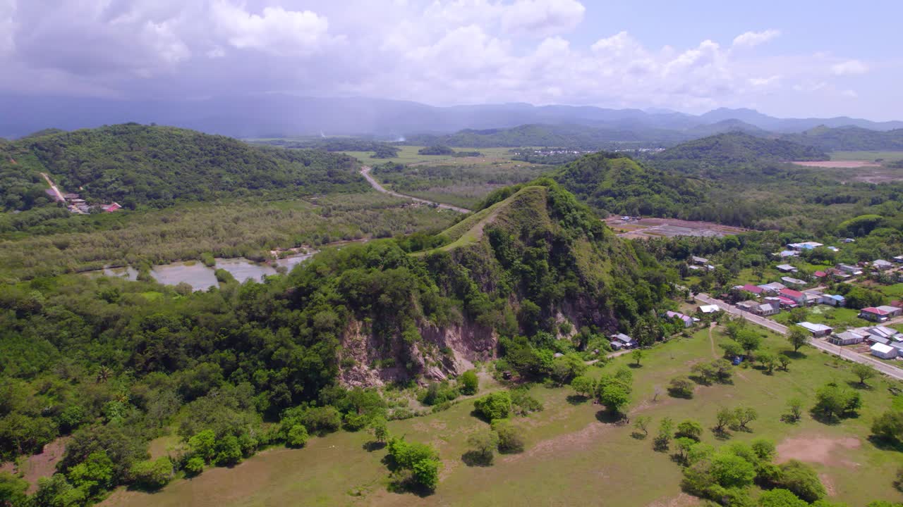 Pemukiman pedesaan di lereng bukit dengan kehijauan dan lahan terbuka di Labuan Bajo Flores Indonesia, tampilan udara panoramik sebagai pengenalan.