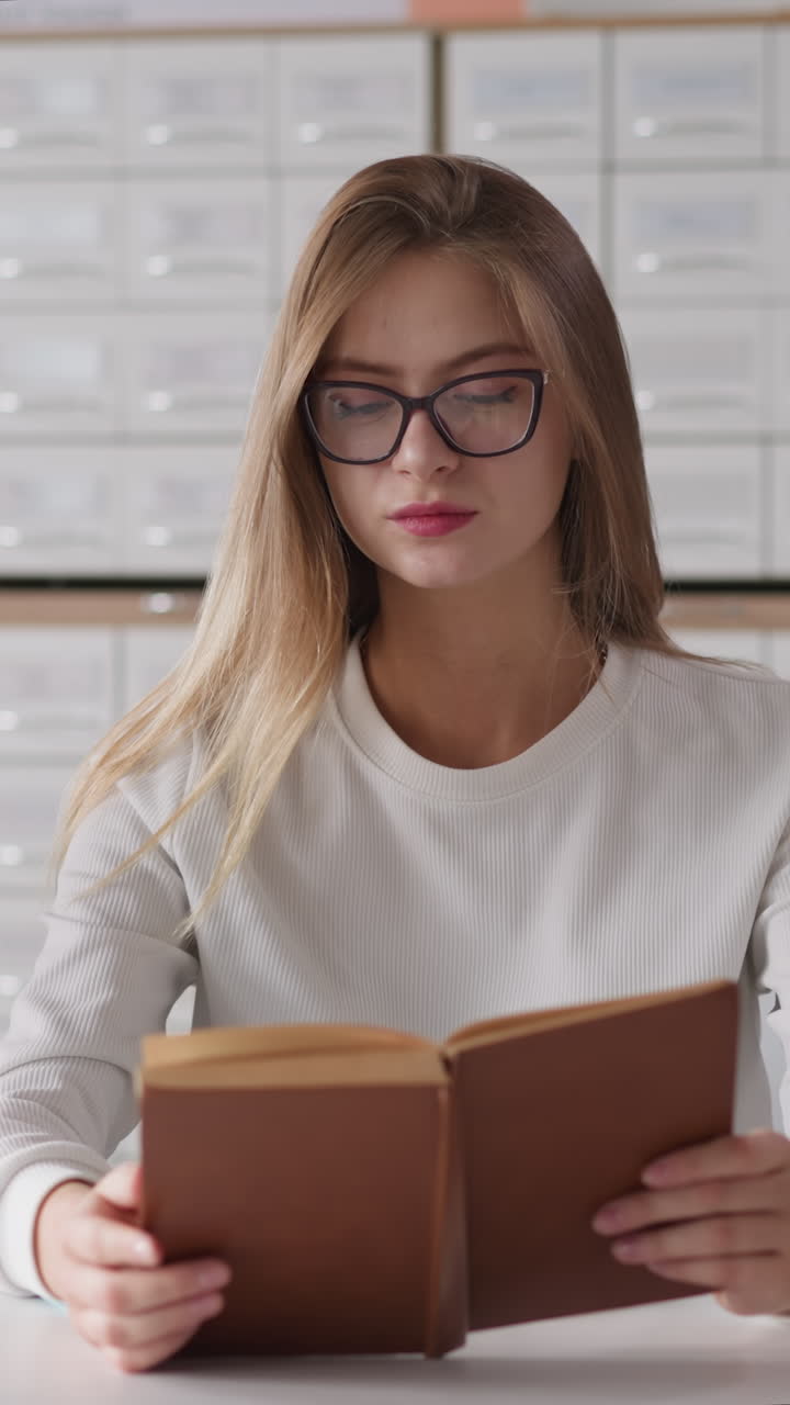 una mujer rubia lee un libro cerca de un hombre negro usando una computadora portátil. una mujer se quita las gafas para descansar durante el material de aprendizaje para futuros exámenes. trabajo duro del estudiante