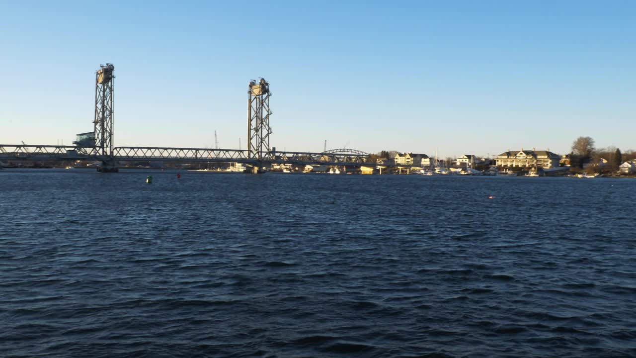 A panning shot of the ocean reveals a city coastline as the sun sets.