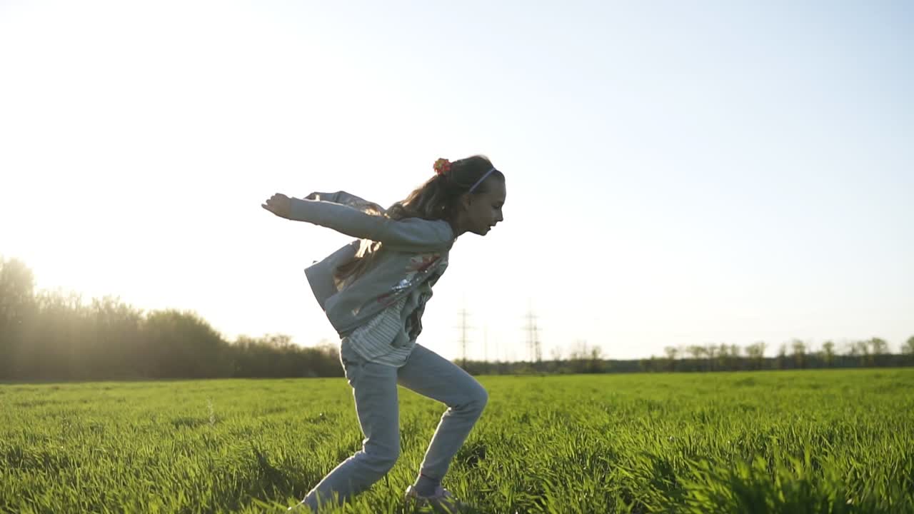 una niña de pelo largo con ropa blanca está jugando al aire libre. hace saltos. un gran prado verde. divertida y despreocupada