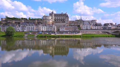 a huge mansion chateau stands perfectly reflected in the waters of the loire river