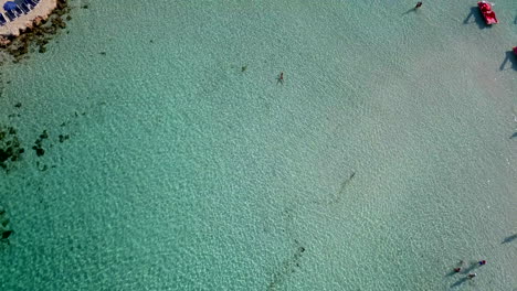 Aerial-overhead-footage-of-people-bathing-at-a-shallow-sandy-beach