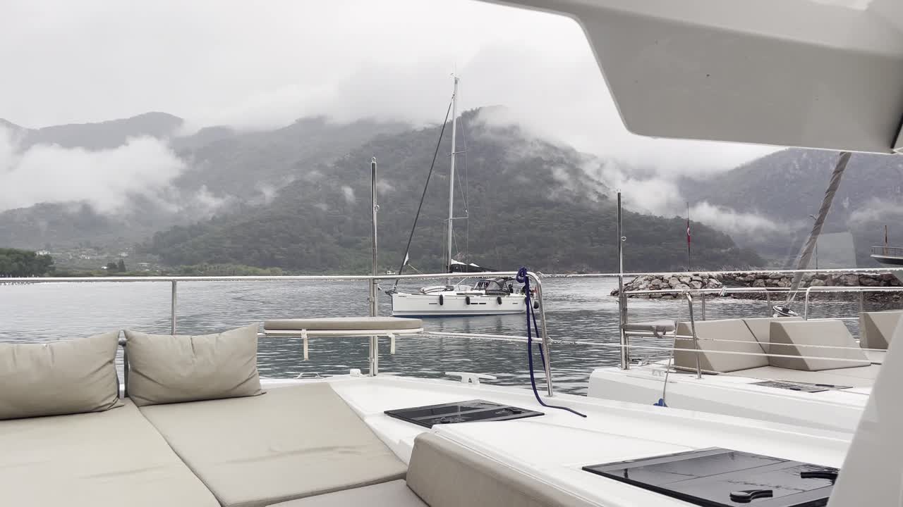 Sailing yacht deck view with misty mountains after rain