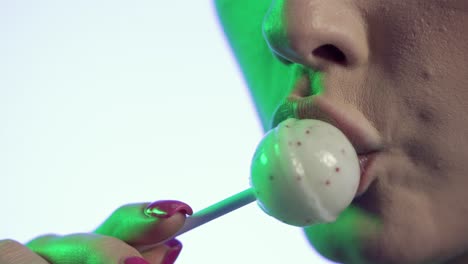 mujer lamendo helado de cereza con seducción, boca en primer plano sobre fondo verde